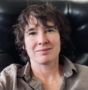 A white woman with short dark hair is smiling at the camera.